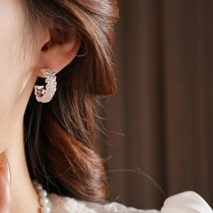 Close-up of 18k gold plated hollow C-shape stud earrings on model with sparkling texture