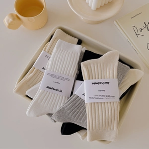 Vertical ribbed cotton socks set in white, beige, grey, and black on a tray