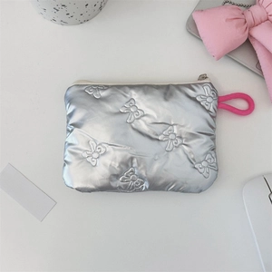 Macro shot of silver quilted cosmetic pouch featuring delicate bow embroidery detail