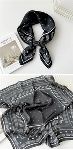 Detail of black paisley silk scarf featuring satin texture and geometric floral pattern