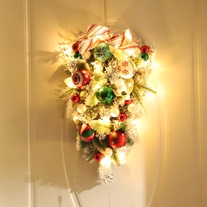 Christmas teardrop wreath with colorful ornaments, striped bow and LED lights on door
