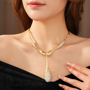 Gros plan d'un collier en Y doré avec pendentif goutte en strass sur un mannequin femme
