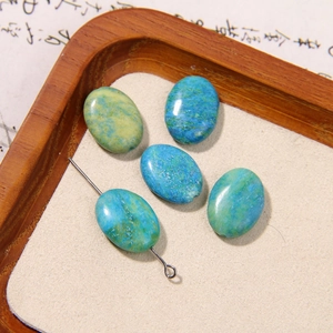 Macro shot of oval natural stone beads with blue yellow texture in a wooden tray