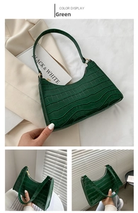 Detail of green crocodile embossed shoulder bag featuring glossy finish and gold zipper
