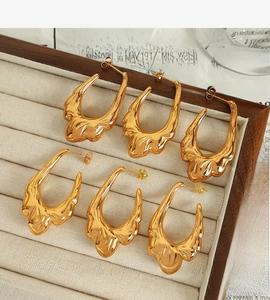 Detailed close-up of three pairs of gold lava-style earrings in a jewelry box storage