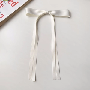 Detailed view of the white satin ribbon bow hair clip with elegant long streamers
