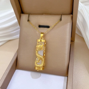 Close-up of golden dragon pendant wrapped around a white cylinder in a jewelry box