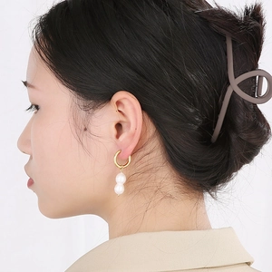 Détail de boucles d'oreilles perles élégantes avec créoles plaquées or 18k sur un mannequin