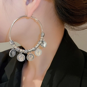 Macro detail of vintage silver hoop earrings with queen portrait coins and beads