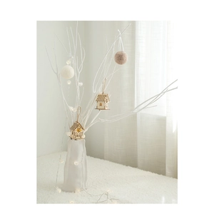 Detail of a minimalist wooden Christmas house ornament with warm LED lights on white branches