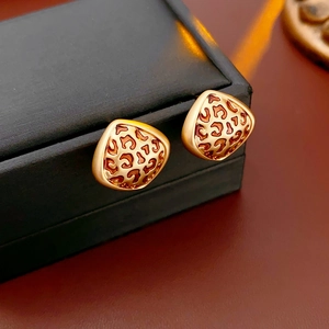 Gros plan sur les boucles d'oreilles triangulaires dorées avec motif léopard émaillé