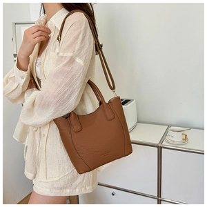 Détail du sac seau en cuir marron avec motif litchi et bandoulière réglable