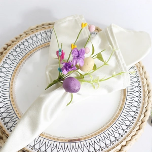 Easter napkin ring featuring purple eggs, faux flowers, and greenery on white plate