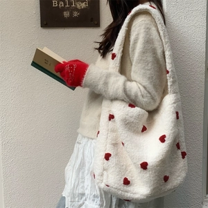 Plush heart-embroidered white tote bag styled as a shoulder bag on female model