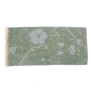 Macro detail of green boucle yarn scarf with light blue floral jacquard and soft fringe