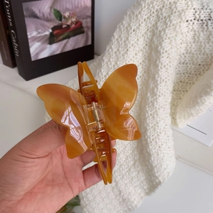 Macro shot of an amber butterfly claw clip with Angeline handmade lettering detail