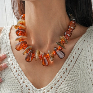 Détail de collier en perles acryliques ambre montrant la texture et l'éclat de résine