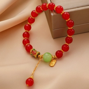 Détail d'un bracelet en perles rouges avec pendentif doré Ping An sur soie champagne