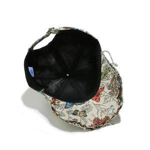Macro shot of jacquard fabric baseball cap featuring butterfly embroidery and distressed edges