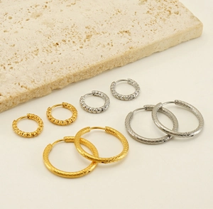 Détails de boucles d'oreilles créoles texturées or et argent sur présentoir pierre