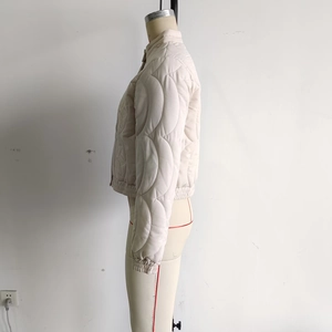 Close-up of cream quilted jacket featuring stand collar and floral textured stitching