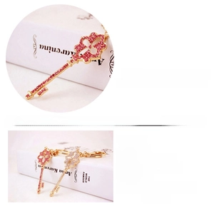 Detail of four-leaf clover key pendant with pink and white rhinestones on zinc alloy base
