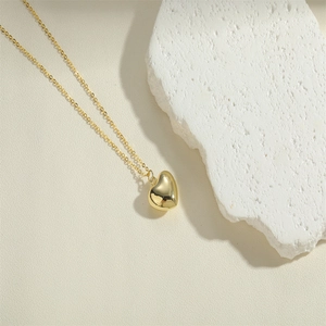 Detailed close-up of a polished gold heart pendant necklace on a textured stone base