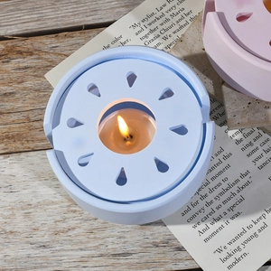 Makroaufnahme der hellblauen Keramik-Duftlampe mit Blüten-Ausschnitten und brennender Kerze
