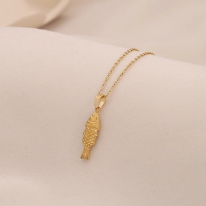 Macro shot of gold fish pendant with detailed scale textures on a slim O-chain necklace