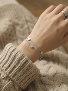 Close-up of double-layer silver heart bracelet on wrist with elegant knitted sleeve