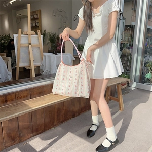 Floral print tote bag with pink handles shown on a wooden bench in a lifestyle setting