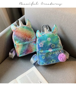 Detail of sequin unicorn backpacks with rainbow patterns and purple pom-pom charms