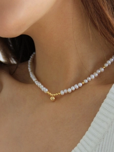 Gros plan d'un collier de perles d'eau douce avec un pendentif boule dorée sur un mannequin