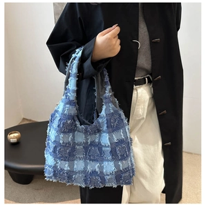 Detail of blue plaid tote bag featuring stylish fringe edges and denim-like texture