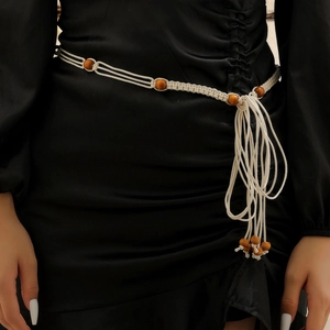 Detail of woven bohemian waist chain with natural wood beads and tassels on black dress