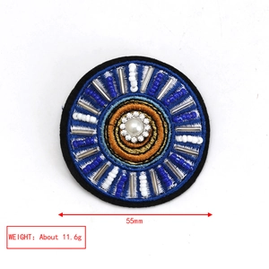 Detail of embroidered Evil Eye brooch with blue beads, faux pearl, and 55mm diameter