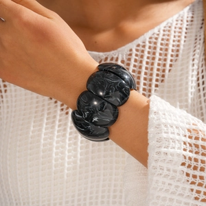 Close-up of marble pattern resin bangle bracelet on a model wearing white knitwear