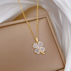 Detailed shot of golden four-leaf clover necklace with cat eye stone and crystal inlay