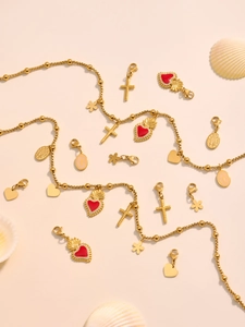 Detail von goldenen Kugelkettchen mit Herz-, Kreuz- und roten Emaille-Blumenanhängern