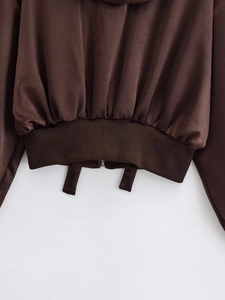 Detail of coffee brown jacket featuring a metallic zipper and ribbed hemline texture