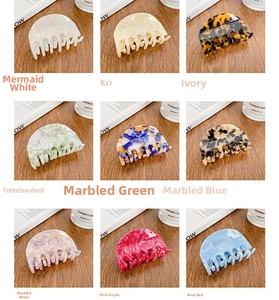 Nine colorful acetate hair claws in various patterns on a wooden table with props