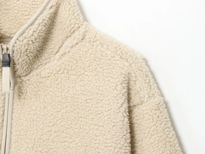 Detailed close-up of cream fleece texture and half-zip collar on women's loose sweatshirt