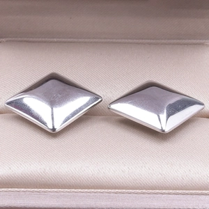 Detailed macro shot of polished geometric diamond-shaped stainless steel stud earrings