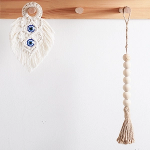 Detail of bohemian woven cotton leaf wall hanging with blue evil eye beads and wood beads
