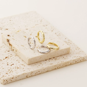 Close-up of S925 sterling silver and gold hoop earrings with cubic zirconia on stone base