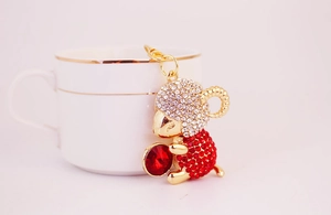 Close-up of golden sheep keychain with sparkling red and clear crystals by a coffee cup