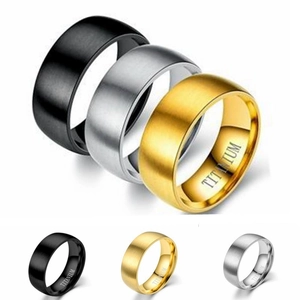 Macro shot of brushed titanium rings in black, gold, and silver showing internal engraving