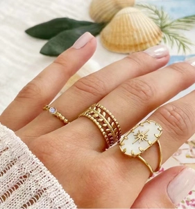Three-piece gold ring set with zircon, leaf texture, and starburst motif on model hand