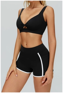 Dettaglio reggiseno sportivo nero con nodo e pantaloncini a vita alta con bordo bianco