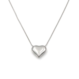 Macro detail of a 3D silver heart pendant on a delicate snake chain with mirror finish